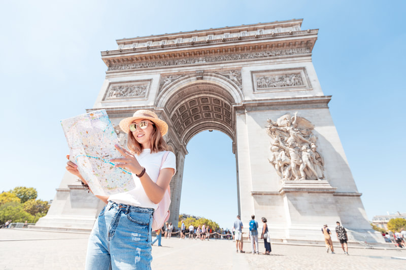Woman looking at a map in front of the Arc De Triomphe
